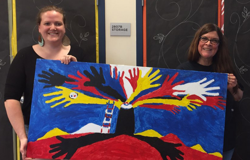 Nancy Rourke holding a painting up with Emily